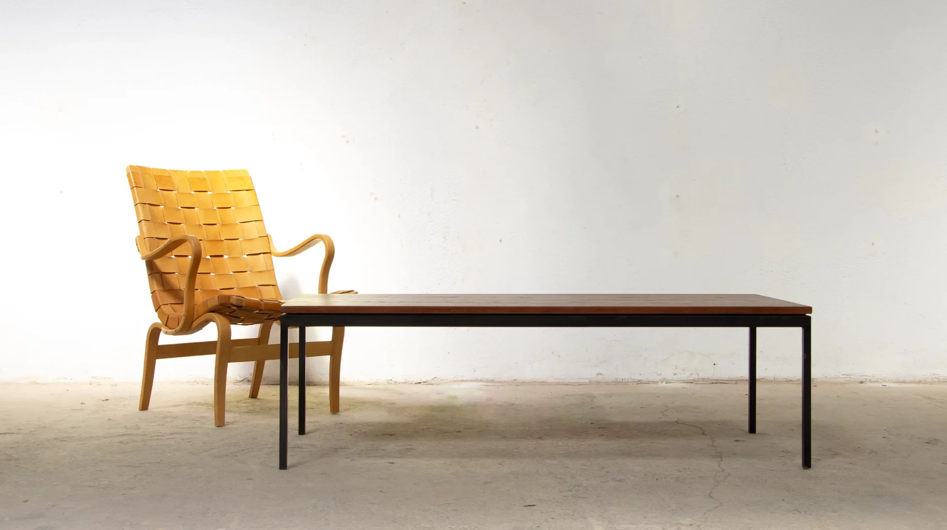 vue d'ensemble de la table basse Florence Knoll en teck et métal noir, accompagné du fauteuil EVA en cuir cognac de Bruno Mathsson pour dux