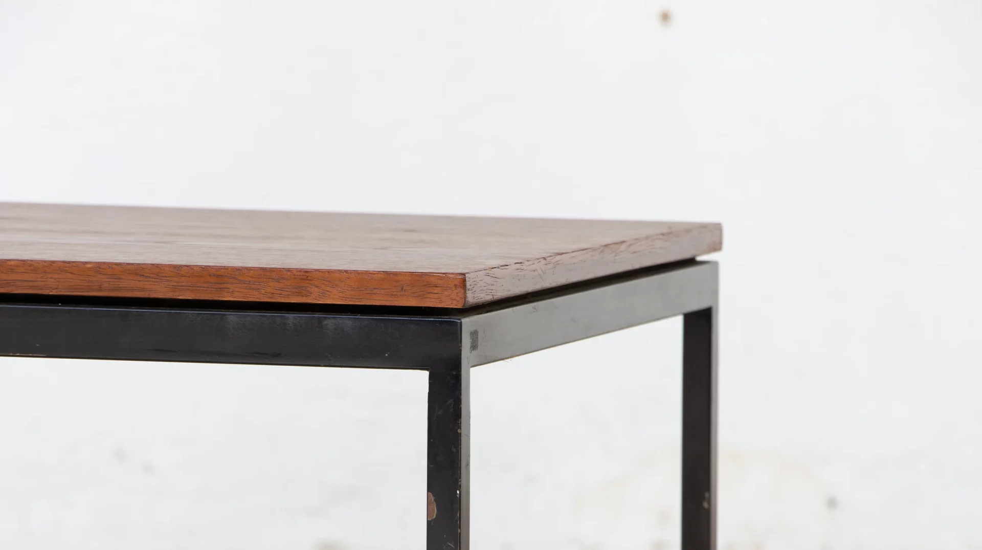 Détail d'un coin de table basse Florence Knoll : teck et piétement métallique noir