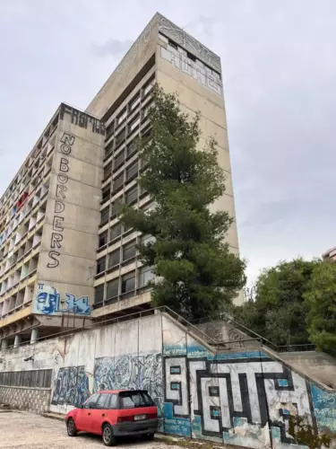 Façade monumentale en béton brut de la résidence étudiante à Athènes, abandonnée avec ses grafs et tags.
